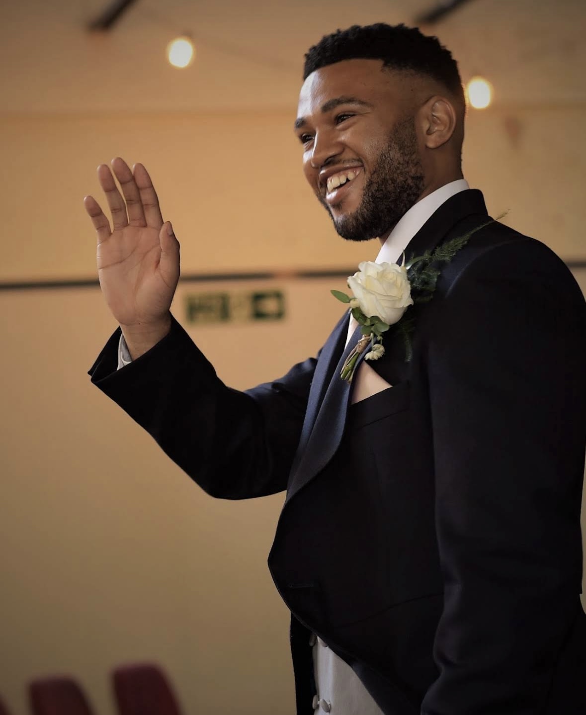Smiling groom waving during a wedding celebration