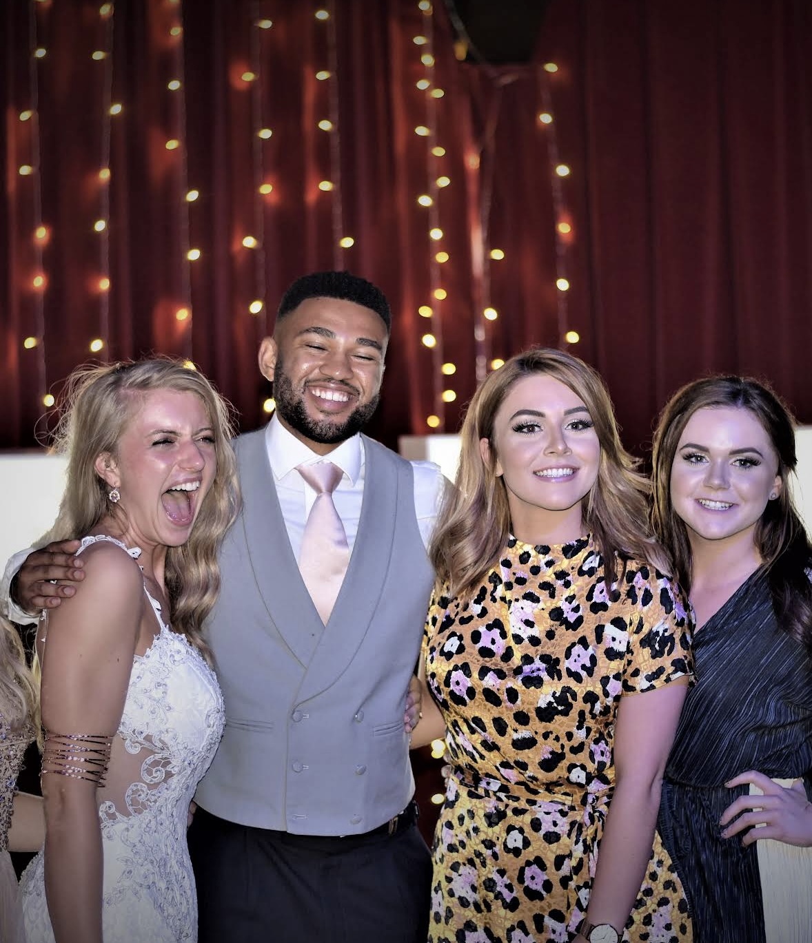 Wedding party smiling together beneath warm lights